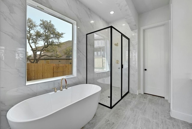 bathroom featuring tile walls and separate shower and tub