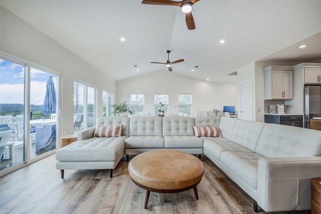 living room featuring a wealth of natural light, vaulted ceiling, and light hardwood / wood-style floors