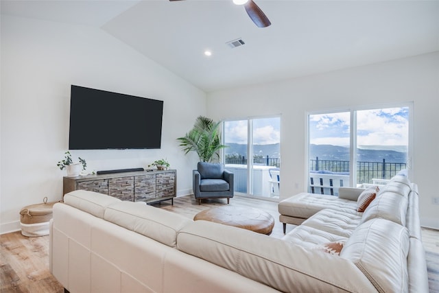 living room with ceiling fan, lofted ceiling, and light hardwood / wood-style floors