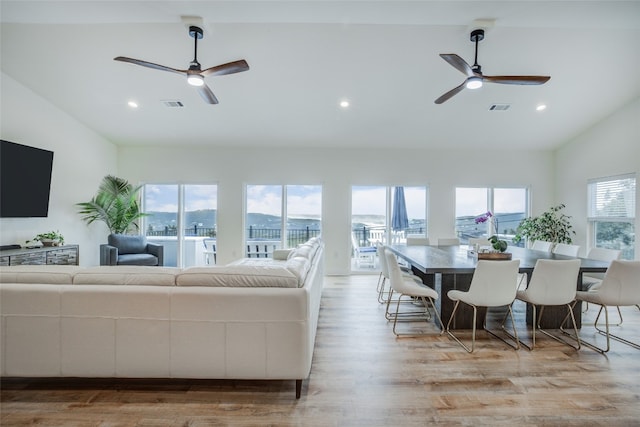 living room with lofted ceiling, ceiling fan, and light hardwood / wood-style flooring