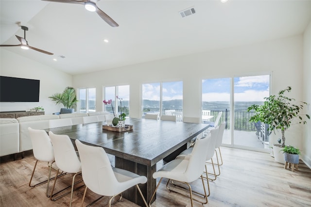 dining space with light hardwood / wood-style flooring, vaulted ceiling, ceiling fan, and a healthy amount of sunlight