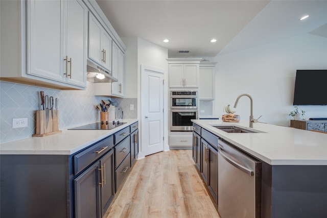 kitchen featuring sink, lofted ceiling, light hardwood / wood-style flooring, decorative backsplash, and appliances with stainless steel finishes