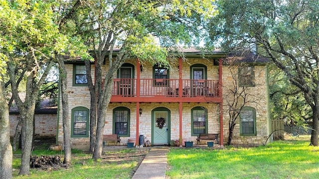 view of front of house featuring a front lawn and a balcony