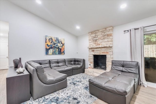 living room with light hardwood / wood-style floors, lofted ceiling, and a fireplace