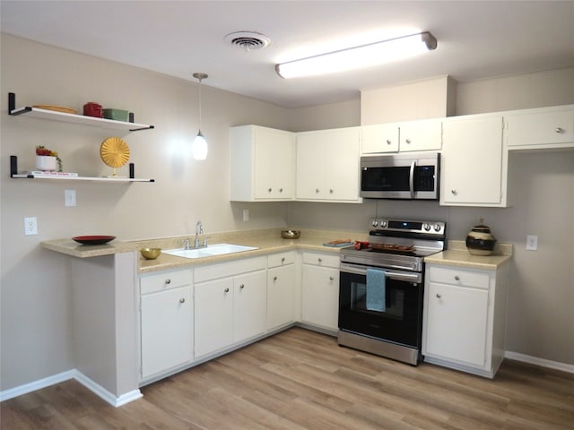 kitchen with hanging light fixtures, light wood-type flooring, white cabinetry, stainless steel appliances, and sink