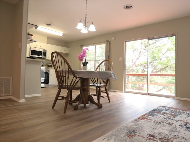 dining space featuring a healthy amount of sunlight, hardwood / wood-style flooring, and an inviting chandelier