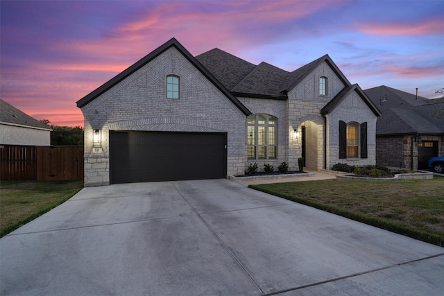 french country style house featuring a garage and a lawn