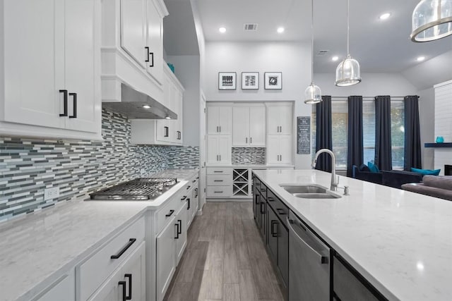 kitchen featuring white cabinetry, backsplash, stainless steel appliances, decorative light fixtures, and sink