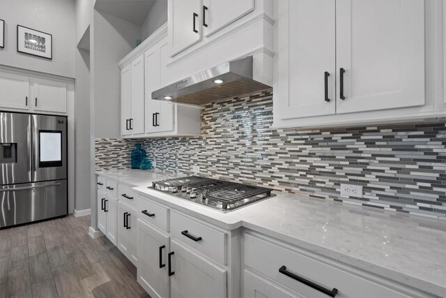 kitchen featuring white cabinets, backsplash, appliances with stainless steel finishes, dark hardwood / wood-style flooring, and wall chimney range hood