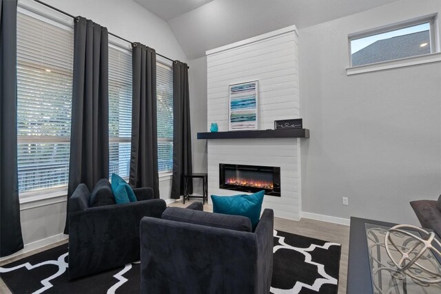 living room featuring lofted ceiling, a large fireplace, and hardwood / wood-style flooring