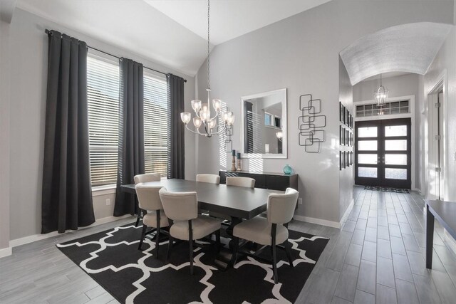 dining space featuring lofted ceiling, light hardwood / wood-style flooring, a notable chandelier, and french doors