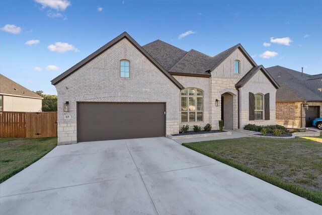 french country home featuring a front yard and a garage