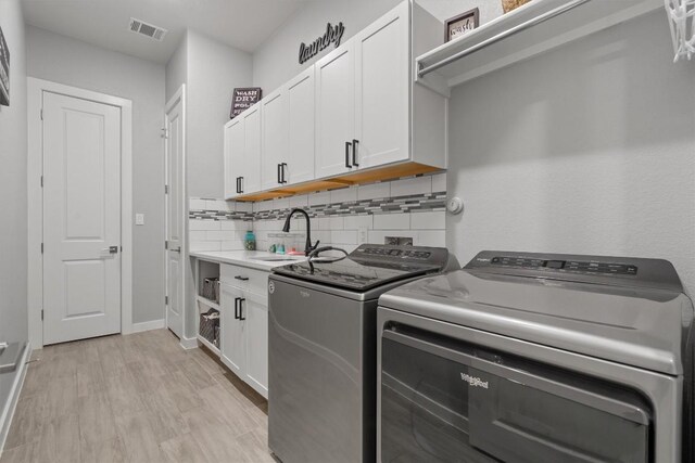 kitchen featuring light hardwood / wood-style flooring, washer and dryer, sink, decorative backsplash, and white cabinets