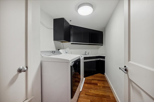 laundry area featuring sink, washer and clothes dryer, dark hardwood / wood-style floors, and cabinets