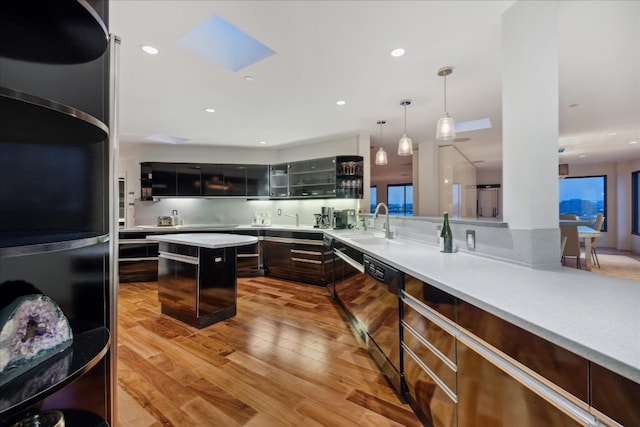 kitchen featuring pendant lighting, light hardwood / wood-style flooring, fridge, black dishwasher, and a skylight