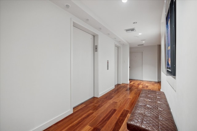 hall with elevator and hardwood / wood-style flooring