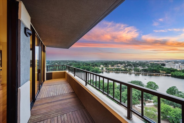 balcony at dusk featuring a water view