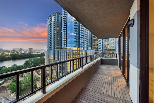 balcony at dusk featuring a water view