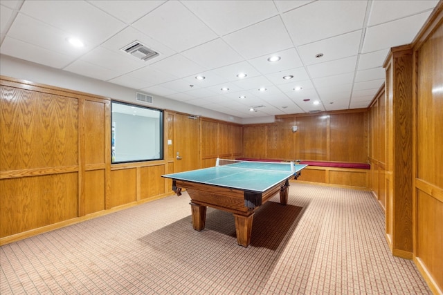 recreation room featuring wooden walls, light carpet, and a drop ceiling