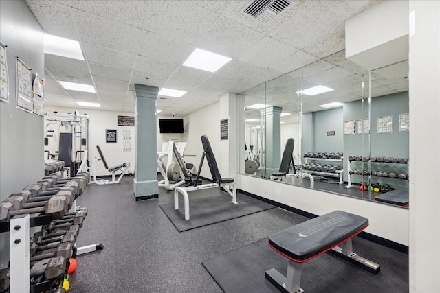 workout area with a drop ceiling and ornate columns