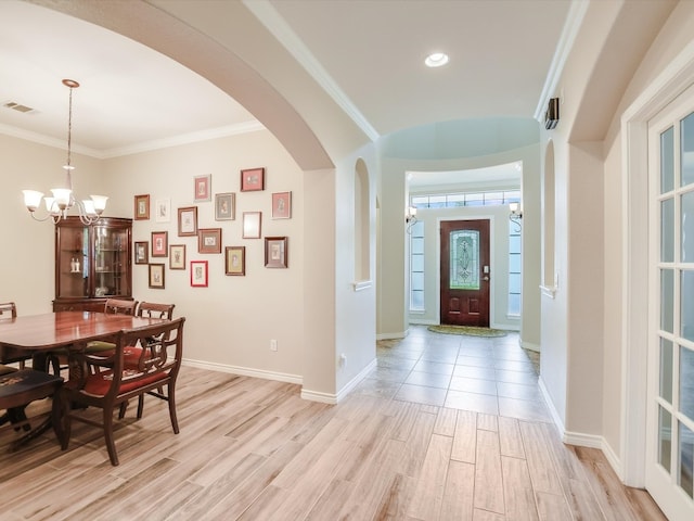 entryway with light hardwood / wood-style flooring, crown molding, and a chandelier