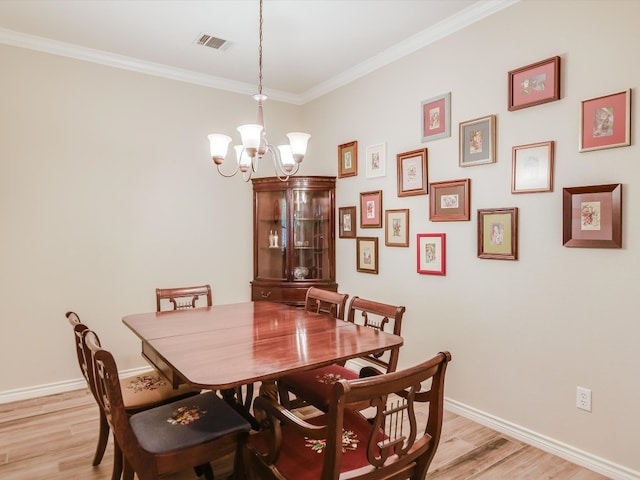 dining area with light hardwood / wood-style floors, a chandelier, and ornamental molding