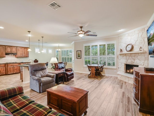 living room with a stone fireplace, light wood-type flooring, ornamental molding, and a healthy amount of sunlight