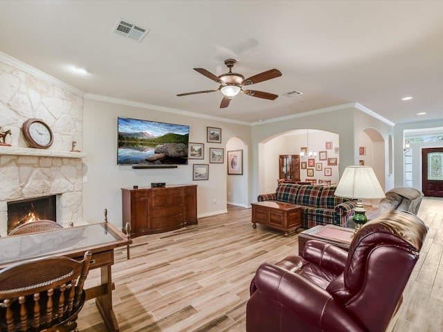 living room with ceiling fan with notable chandelier, light hardwood / wood-style flooring, a fireplace, and ornamental molding