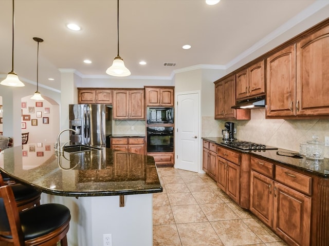 kitchen featuring a breakfast bar area, a center island with sink, and black appliances