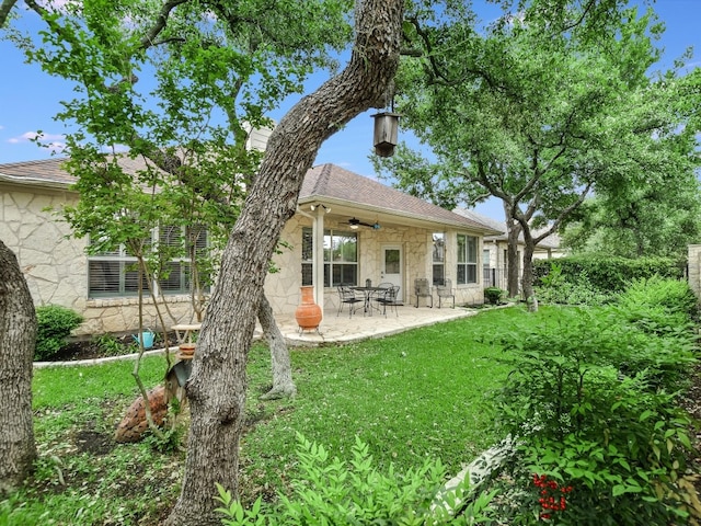 rear view of property with ceiling fan, a patio, and a lawn