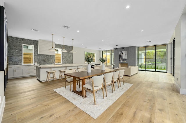 dining area with ceiling fan, light wood-type flooring, and floor to ceiling windows