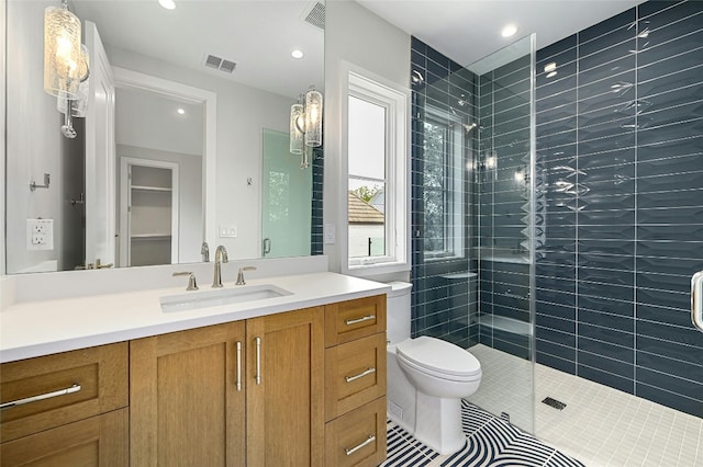 full bathroom with toilet, visible vents, tiled shower, and vanity