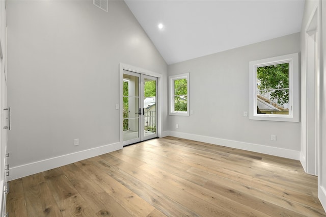 unfurnished room featuring light wood-type flooring, french doors, and high vaulted ceiling