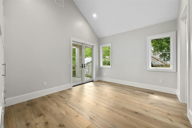 empty room with light wood-style floors, visible vents, high vaulted ceiling, and baseboards