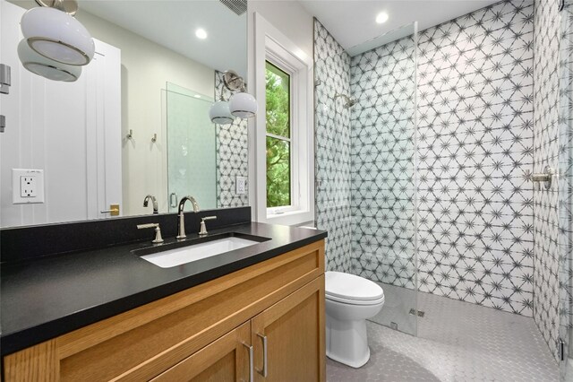 bathroom with walk in shower, vanity, tile patterned floors, and toilet