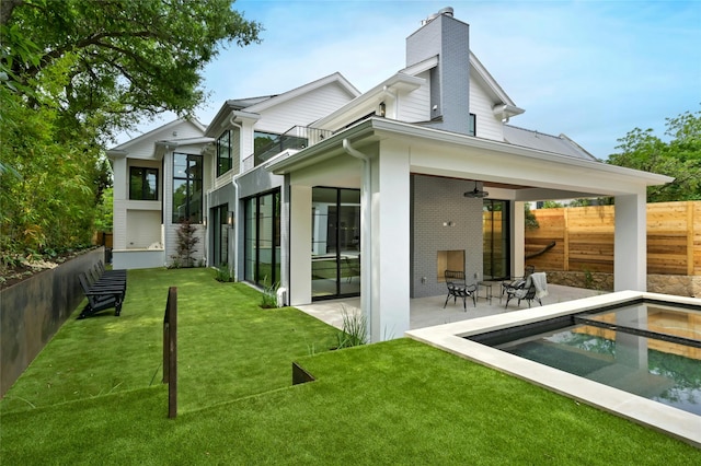 back of property with a chimney, a lawn, a patio area, ceiling fan, and fence