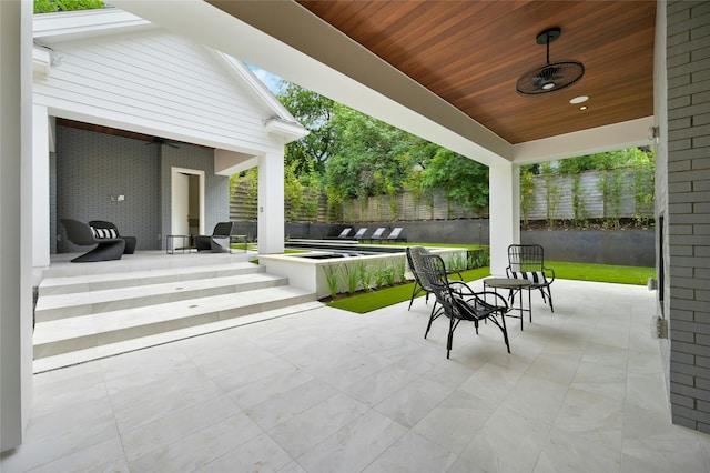 view of patio / terrace with ceiling fan and a hot tub