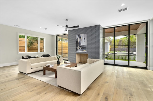 living room featuring ceiling fan, light wood-type flooring, and plenty of natural light