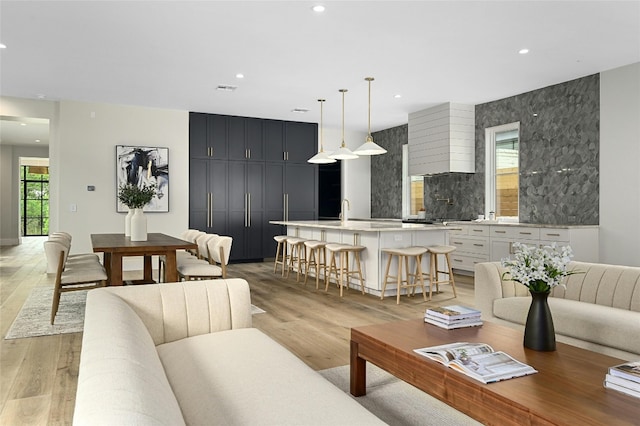 living area with light wood finished floors, visible vents, and recessed lighting