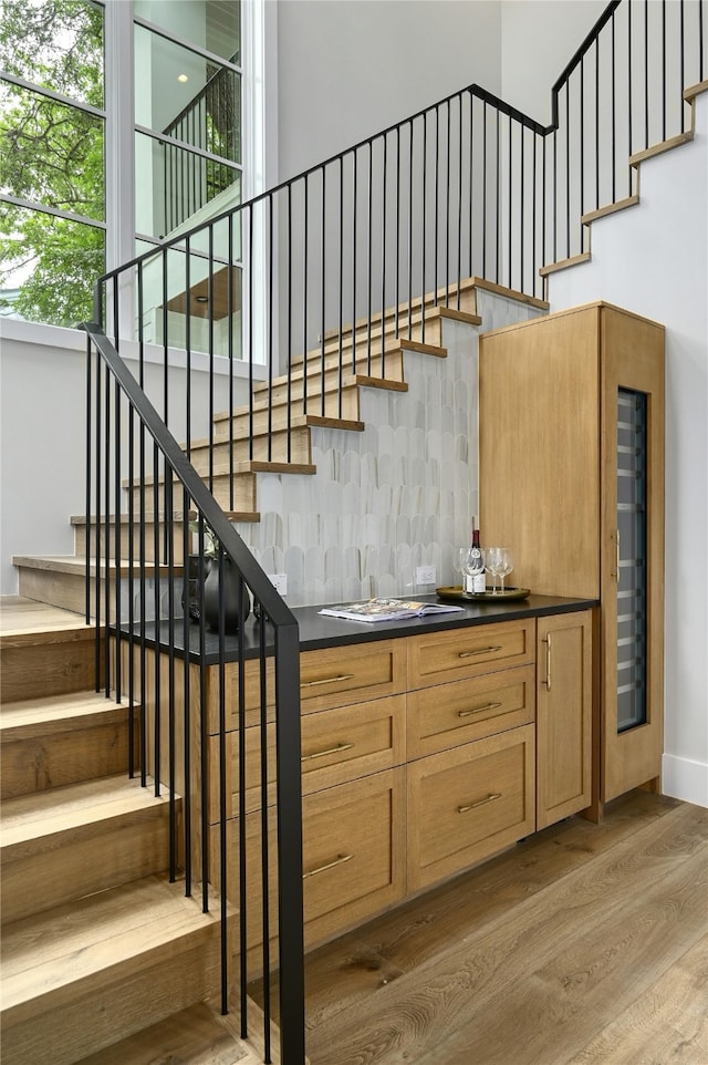 staircase featuring hardwood / wood-style flooring, a high ceiling, and bar area