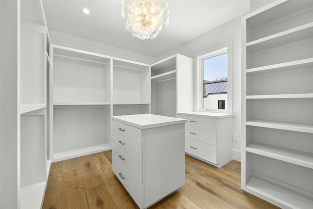 spacious closet featuring light wood finished floors and a notable chandelier