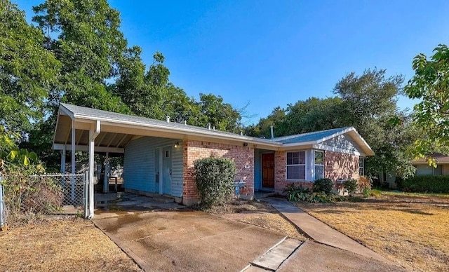 single story home with an attached carport, brick siding, and driveway