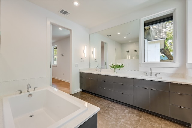 bathroom featuring a bath to relax in, dual sinks, tile floors, and large vanity