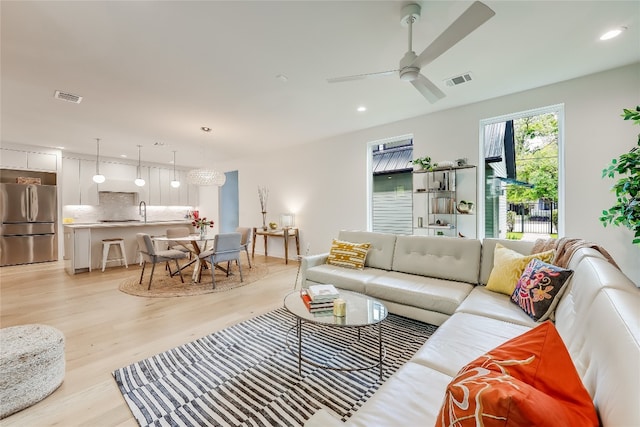 living room featuring ceiling fan, light hardwood / wood-style floors, and sink