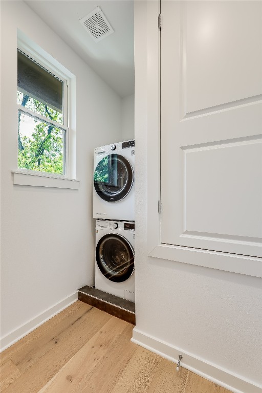 laundry area featuring stacked washer / dryer and light wood-type flooring