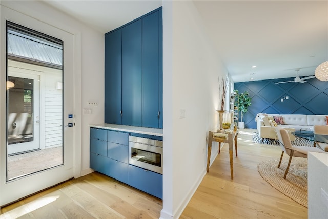 entryway with blue cabinets and light wood-type flooring