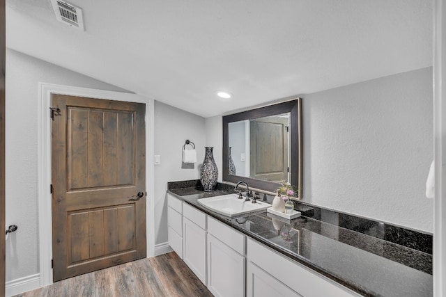 bathroom with hardwood / wood-style flooring, vanity, and lofted ceiling