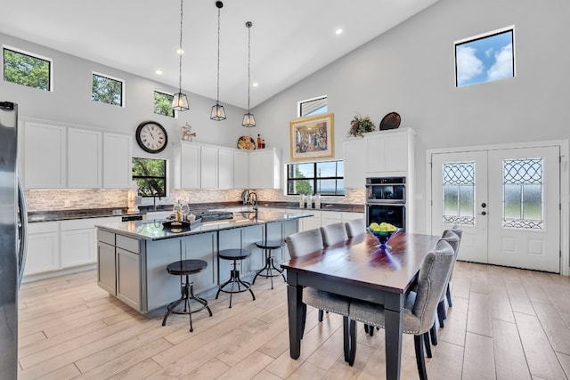 kitchen featuring backsplash, high vaulted ceiling, a kitchen bar, and an island with sink