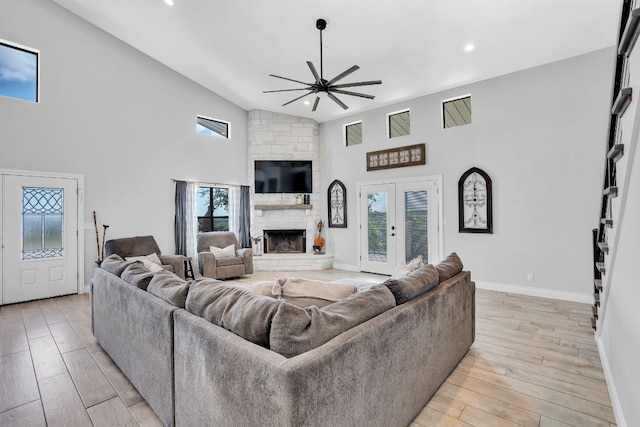 living room featuring a healthy amount of sunlight, light hardwood / wood-style flooring, and a stone fireplace