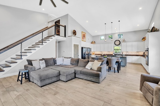 living room with sink, light hardwood / wood-style flooring, and a high ceiling